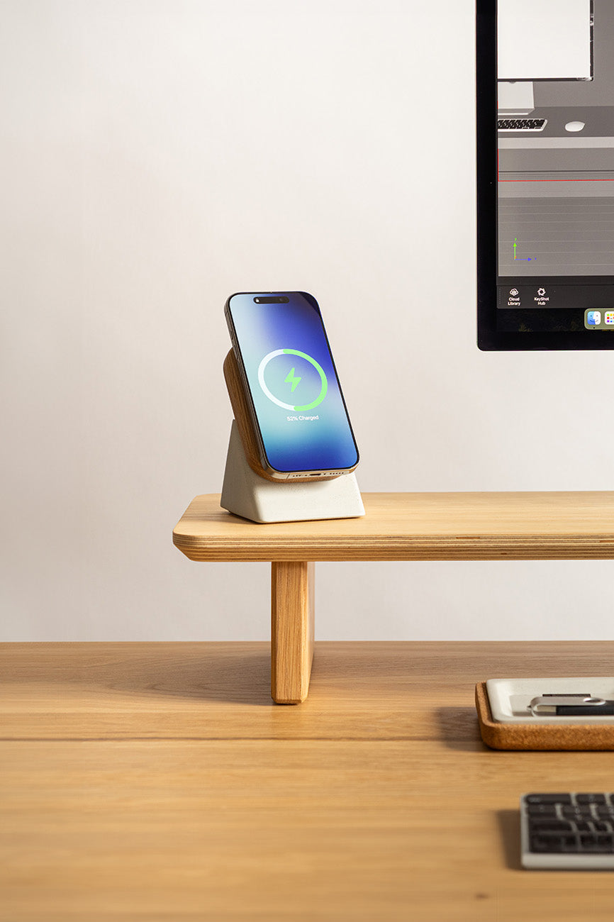 Smartphone on a charging stand with a computer monitor in the background