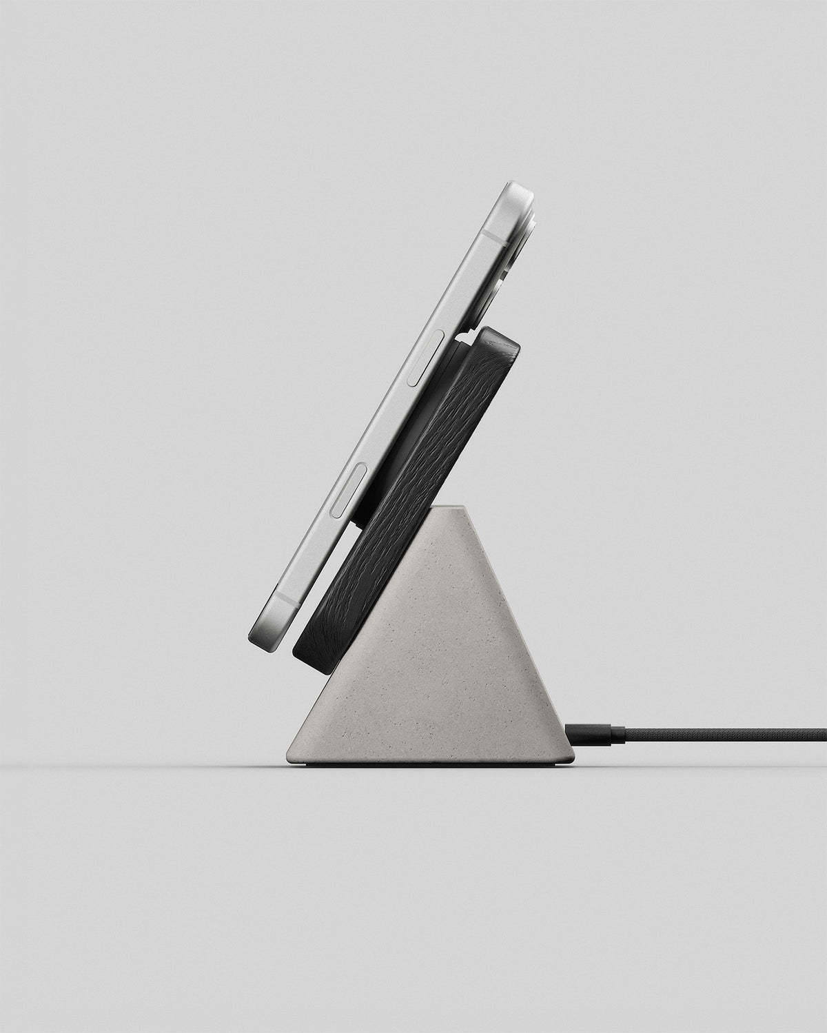 Upright wireless charging stand in black wood and stone concrete, side view with a smartphone charging