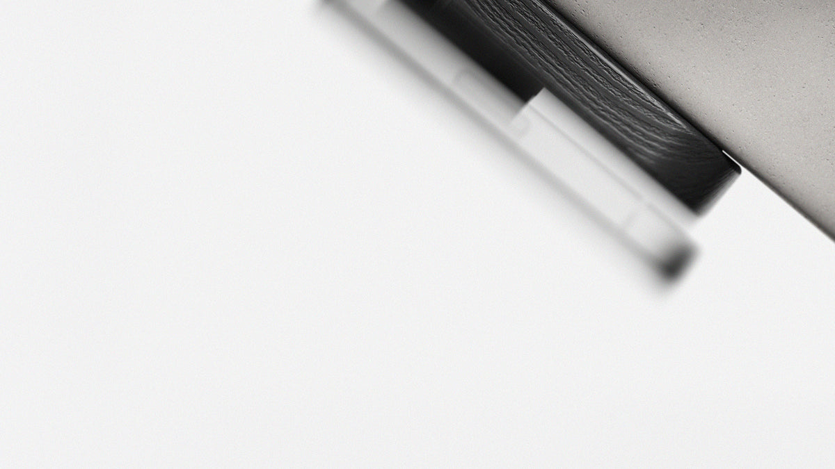 A close-up, abstract black and white photograph of a modern, minimalist charging stand, shown against a solid white background.