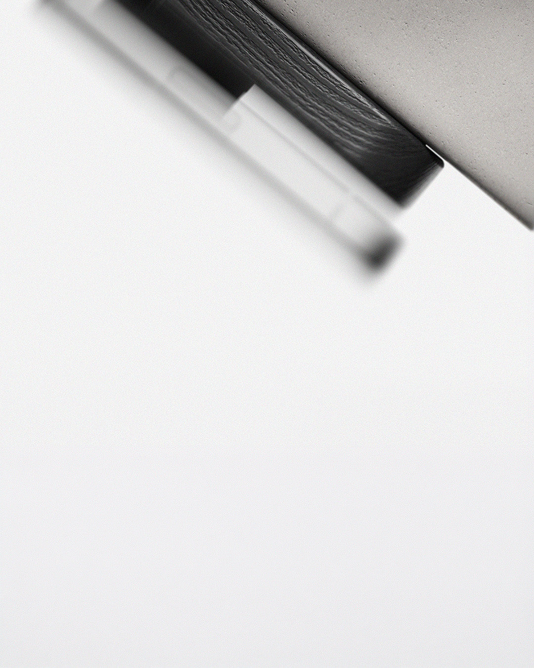 A close-up, abstract black and white photograph of a modern, minimalist charging stand, shown against a solid white background.