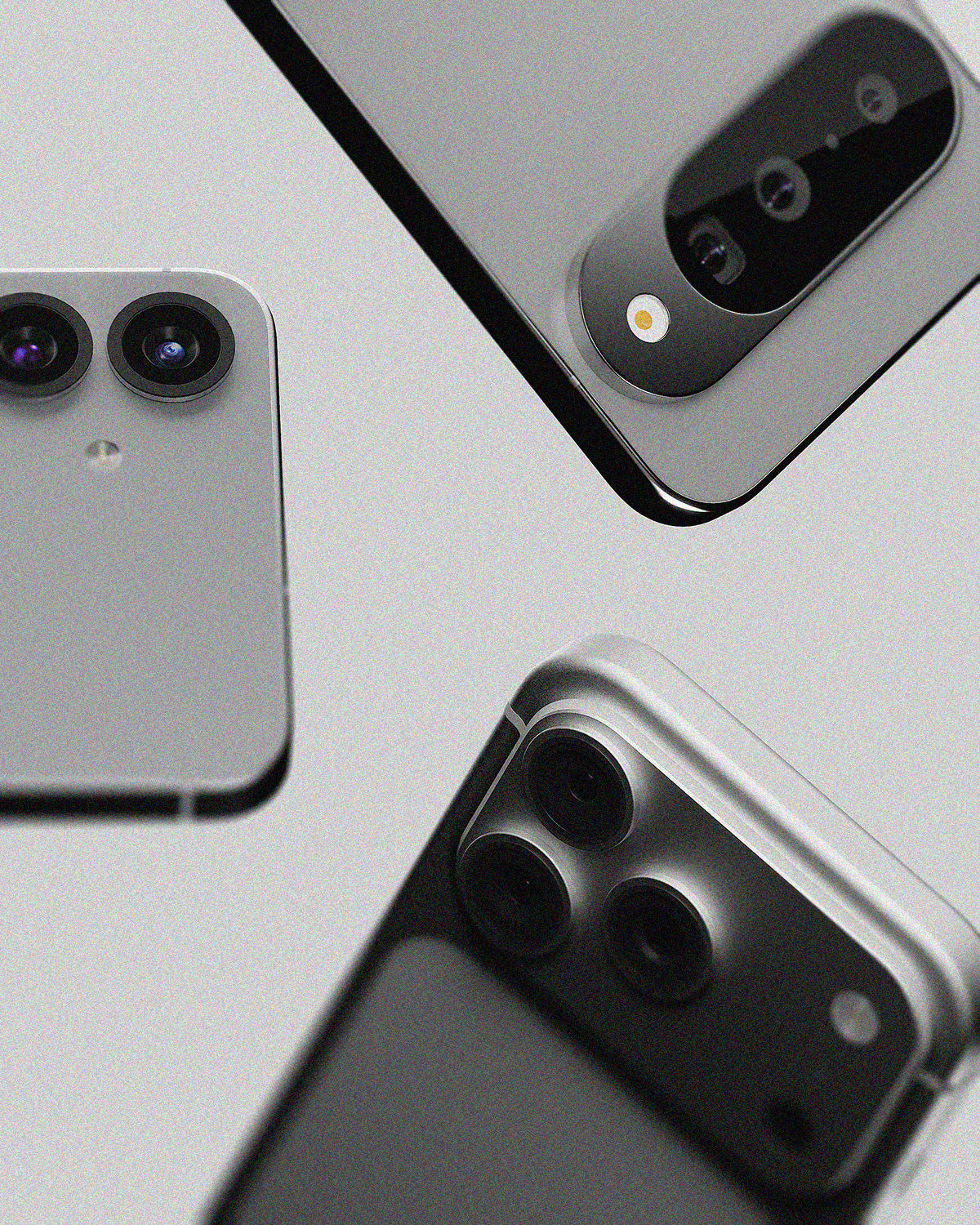 Three smartphone back views arranged diagonally on a light gray background, showing silver and dark gray finishes with large rear camera clusters.