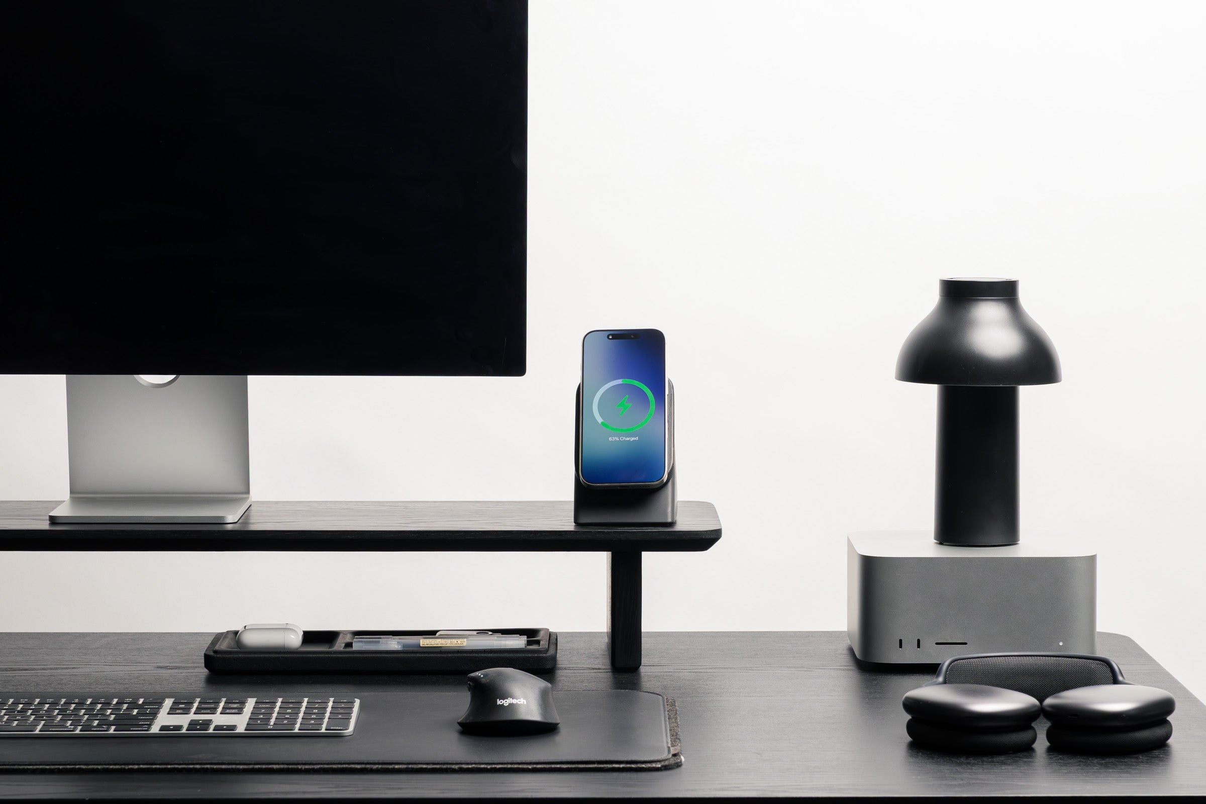 Modern office desk setup with computer monitor, smartphone, and other devices on a white background