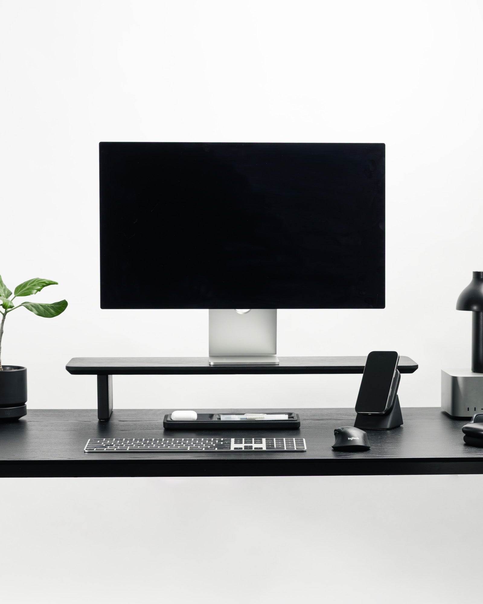 Modern office desk setup with a computer monitor, keyboard, mouse, and phone on a white background