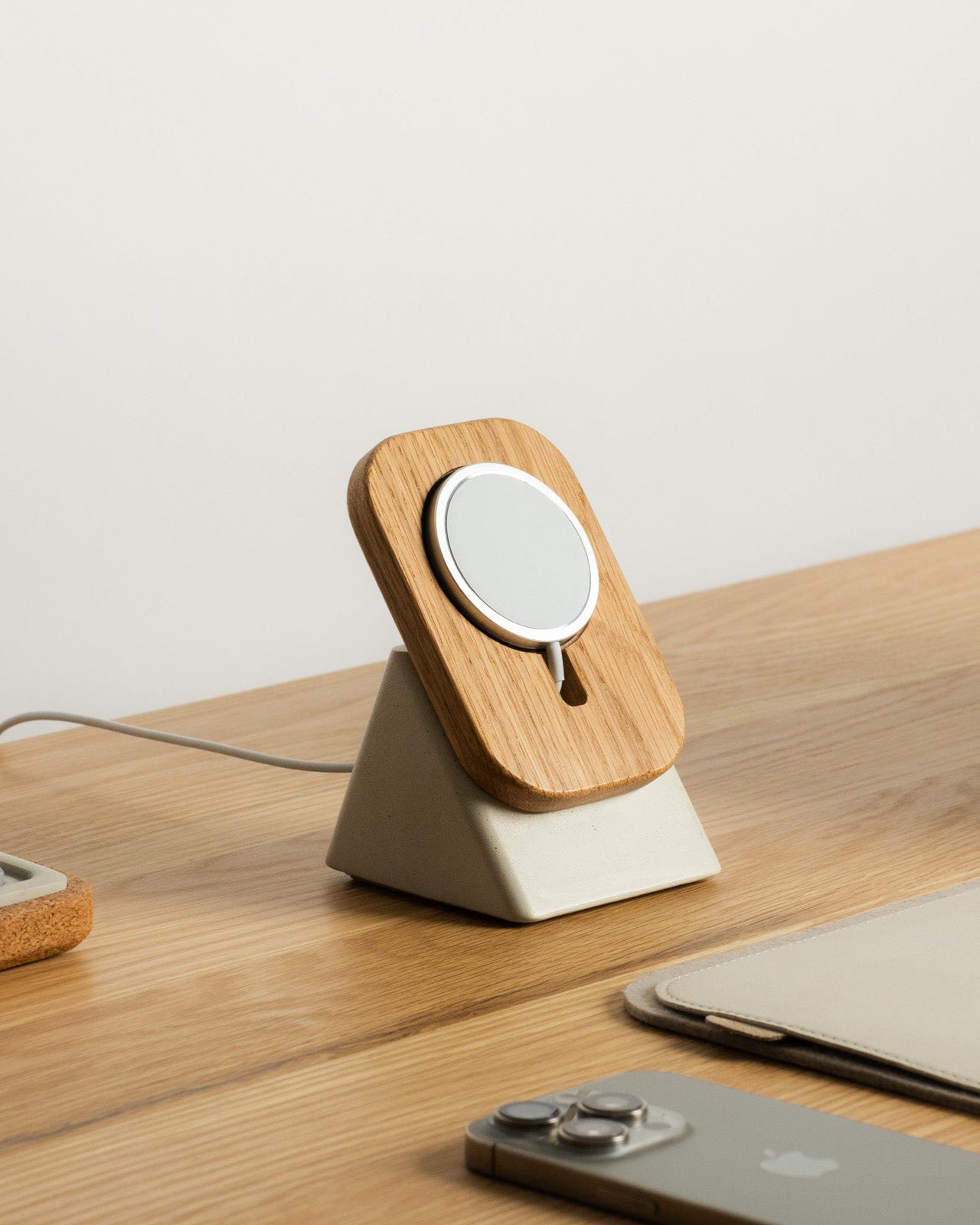 Wooden phone stand on a desk with smartphone, tablet, and notebook