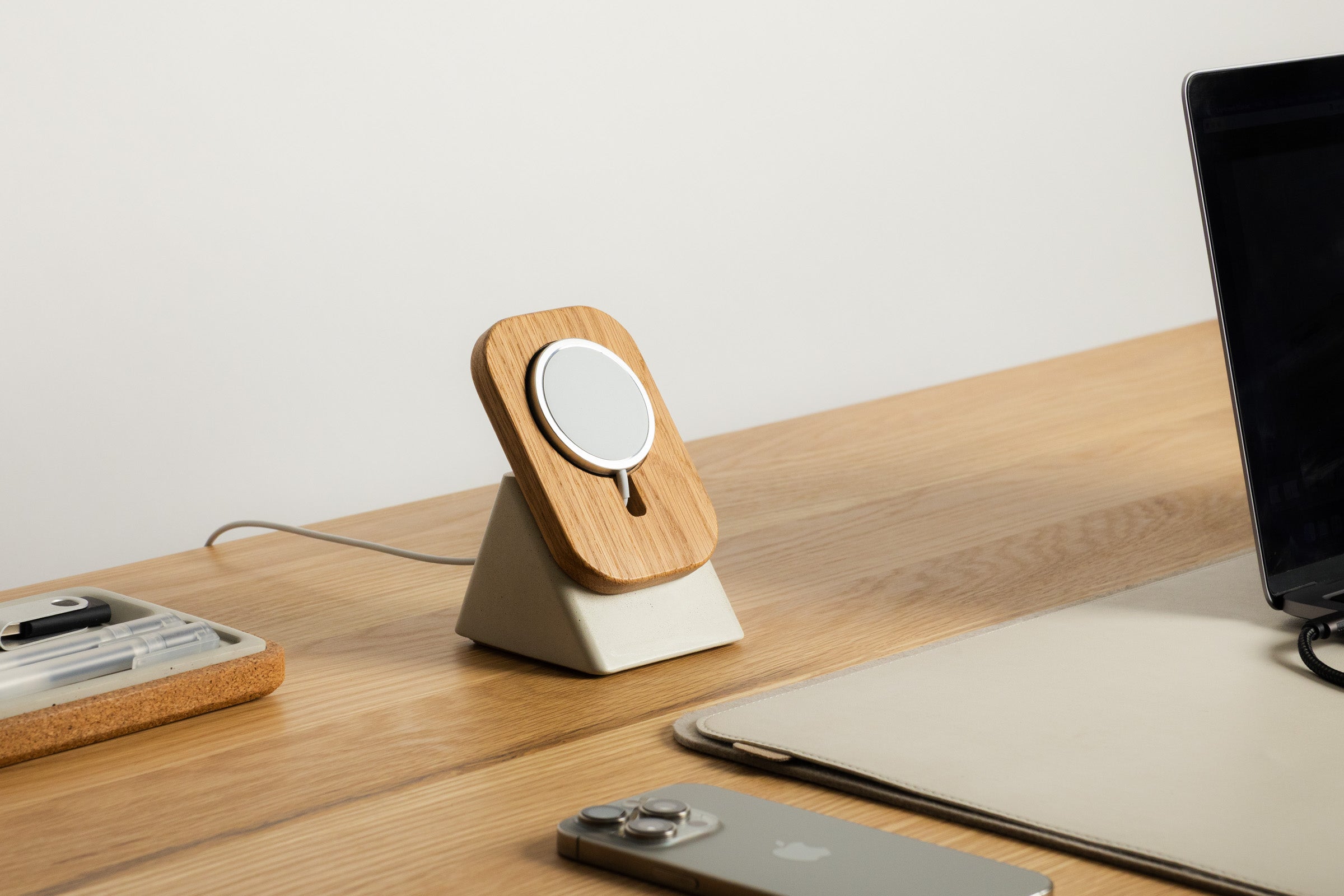 Wooden phone stand on a desk with smartphone, tablet, and notebook
