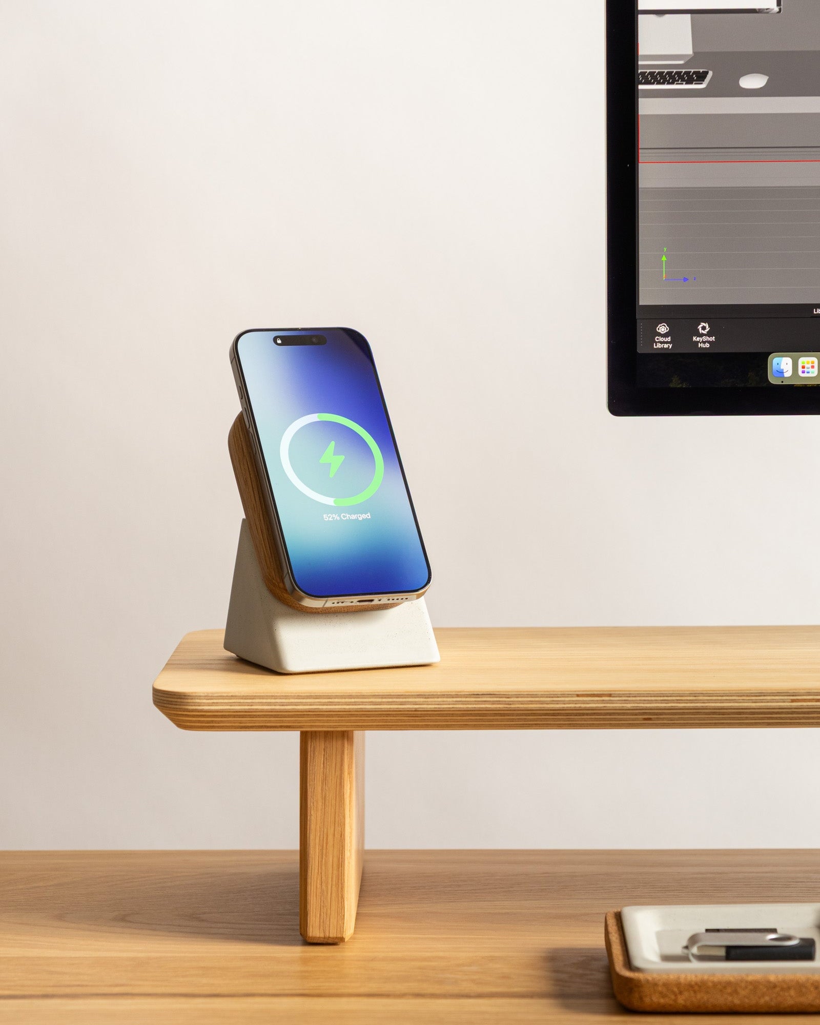 Smartphone on a charging stand with a computer monitor in the background