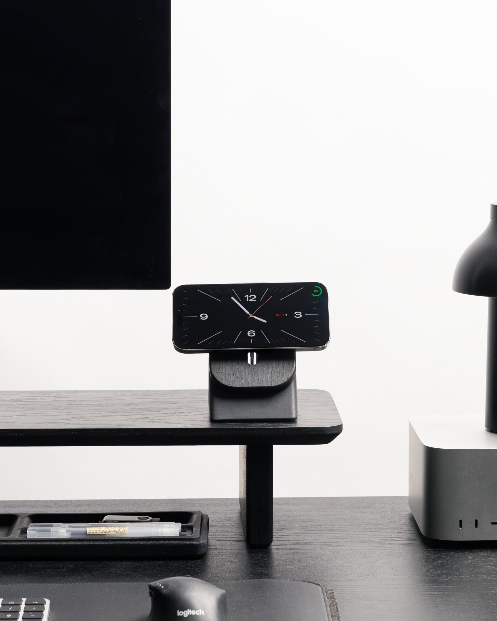 Modern office desk setup with a computer monitor, keyboard, mouse, and smartphone on a minimalistic desk.
