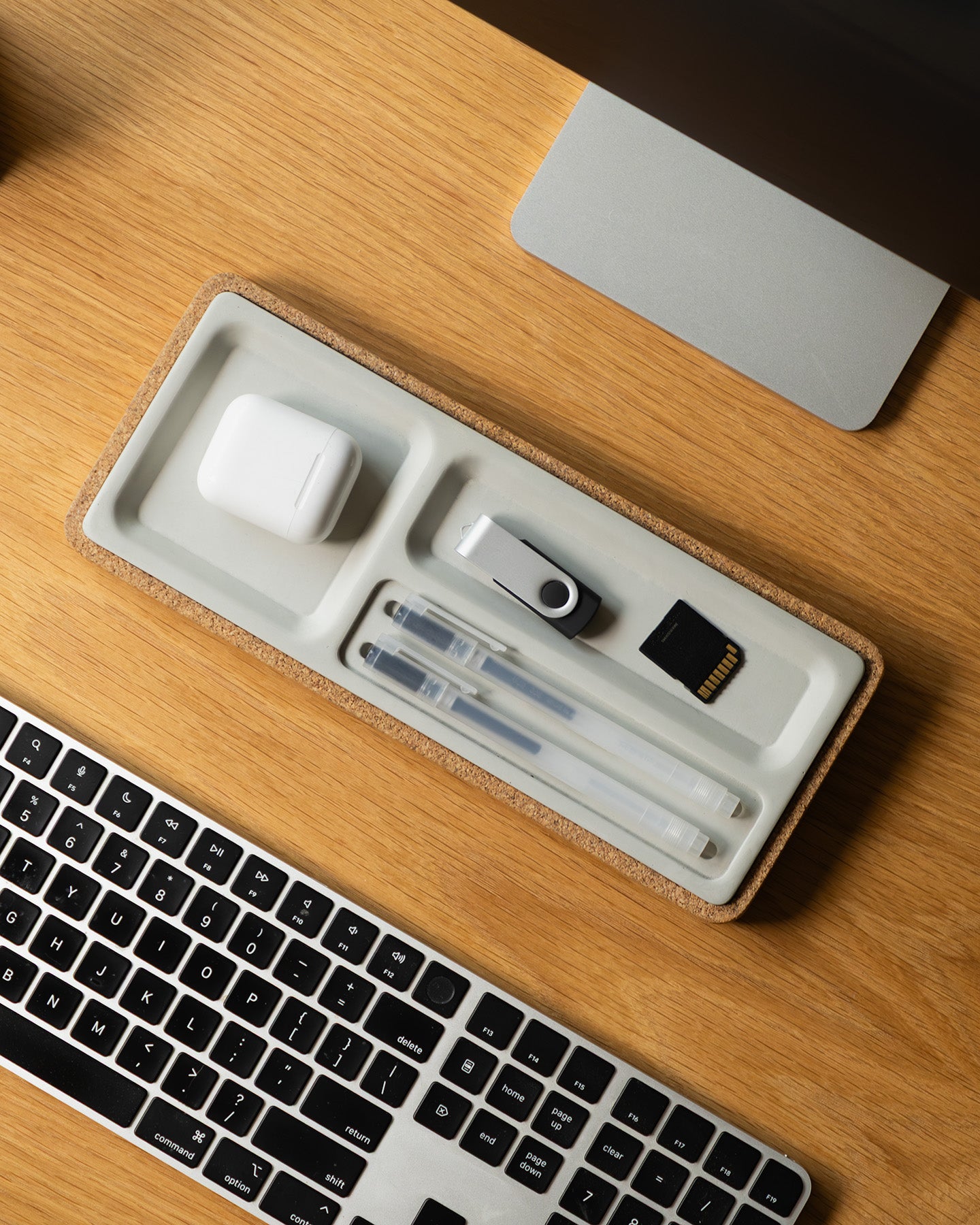Desk setup with a keyboard, mouse, and various electronic accessories on a wooden surface.