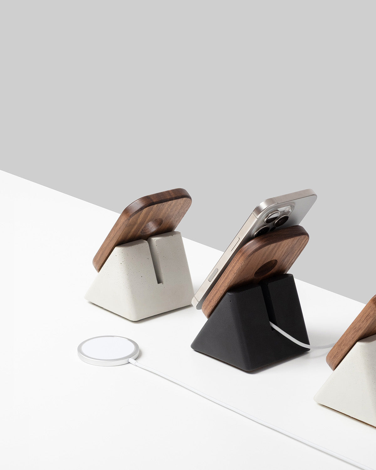 Three phone stands with wooden accents on a white surface