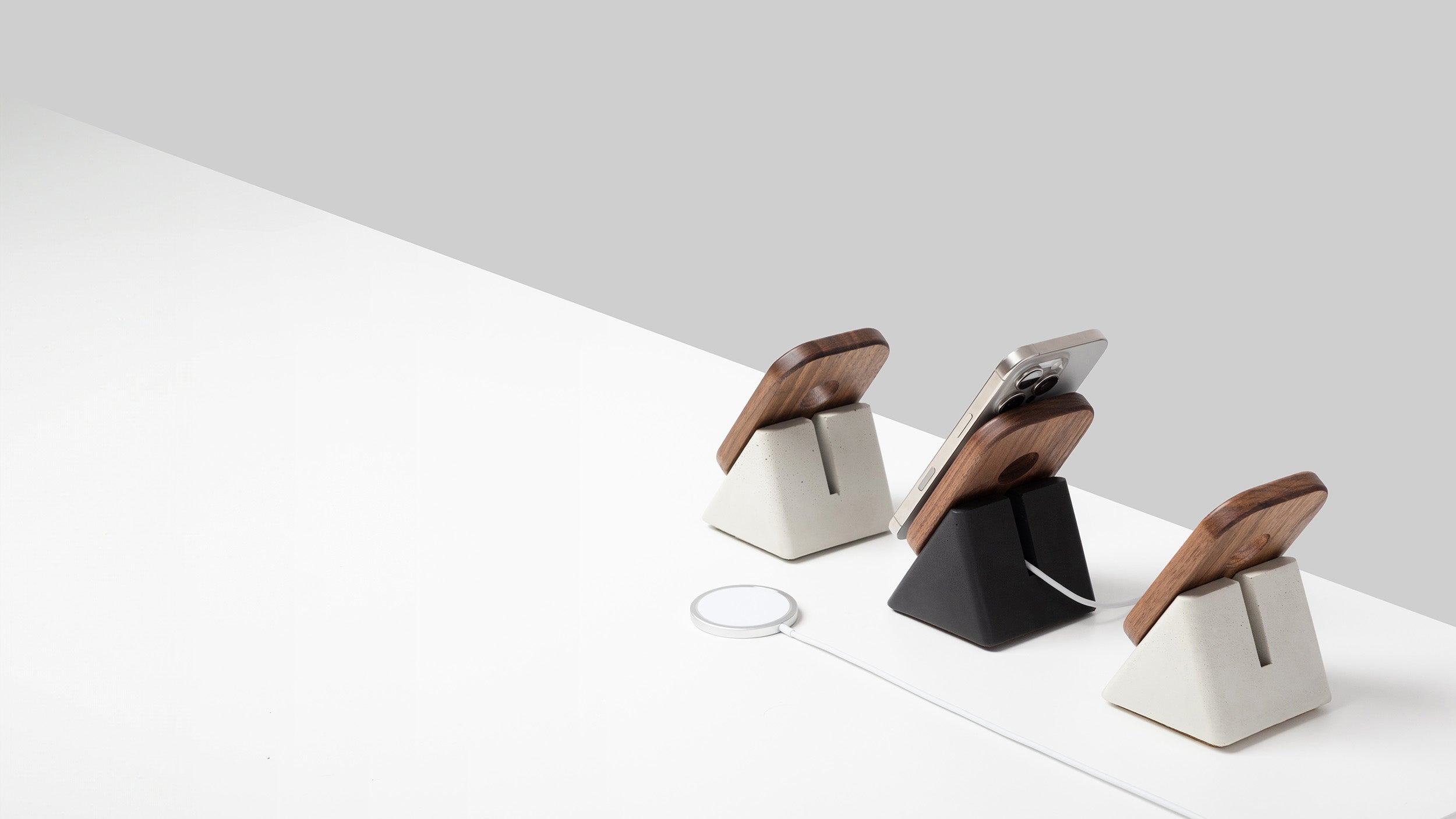 Three modern phone stands on a white surface with a light gray background