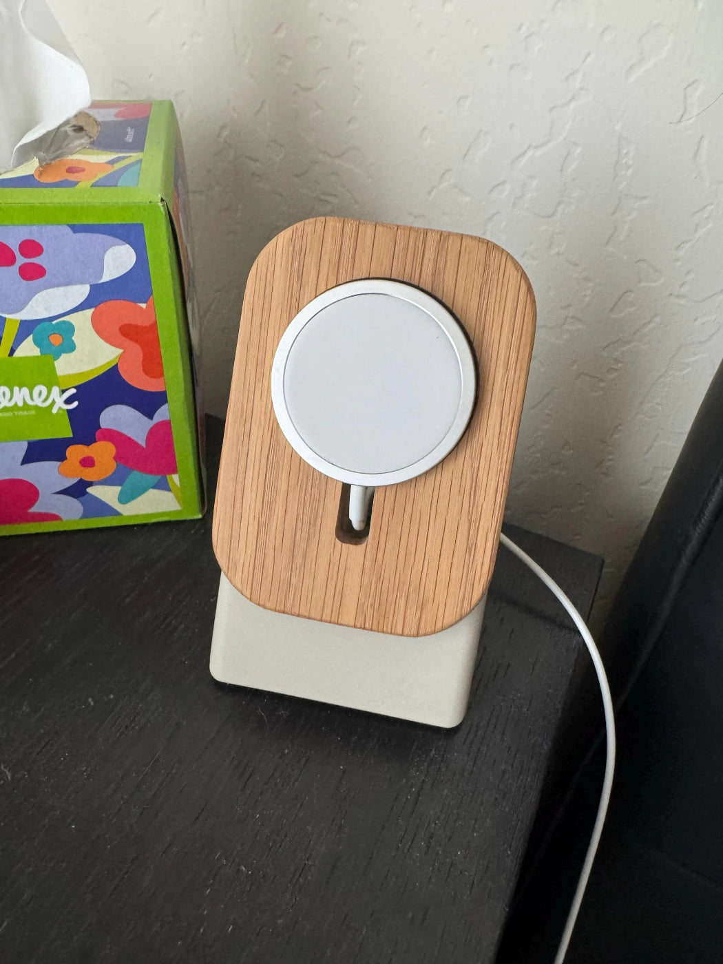 Wooden phone stand with a white device on a dark surface