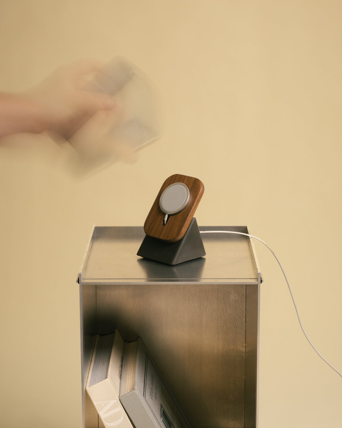 Wooden phone stand on a metallic box with a blurred hand in the background