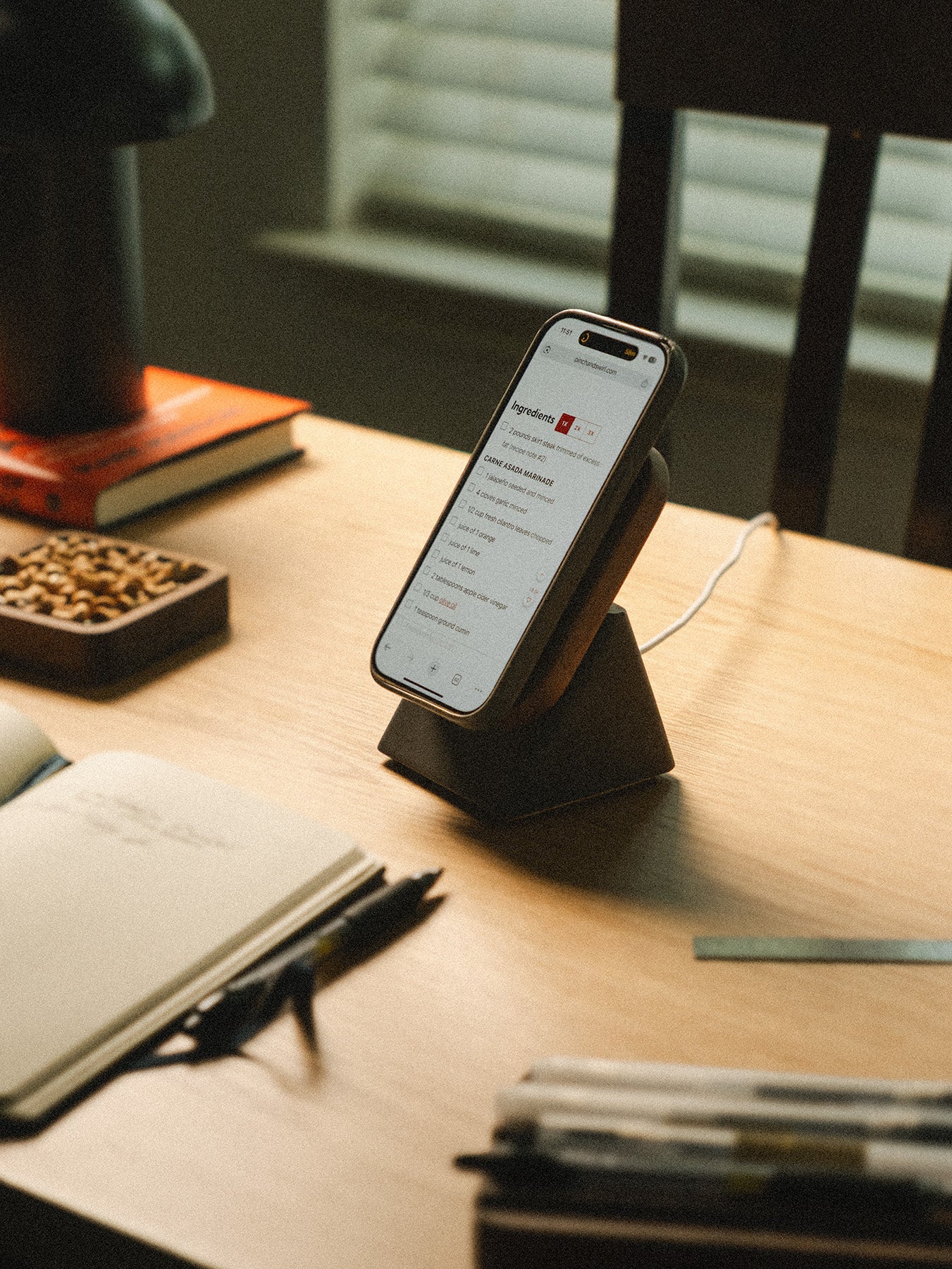 Phone on a stand on a desk with a notebook and pen
